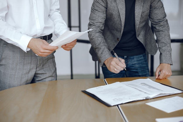 Hombres de negocios sentados en el escritorio de los abogados. Personas que firman documentos importantes.