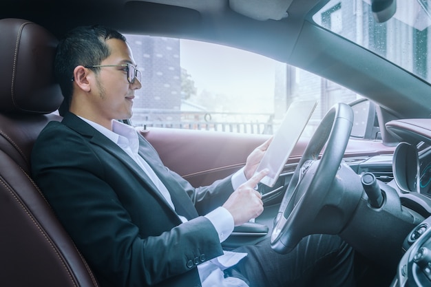 Los hombres de negocios trabajan con las computadoras tablet en sus coches