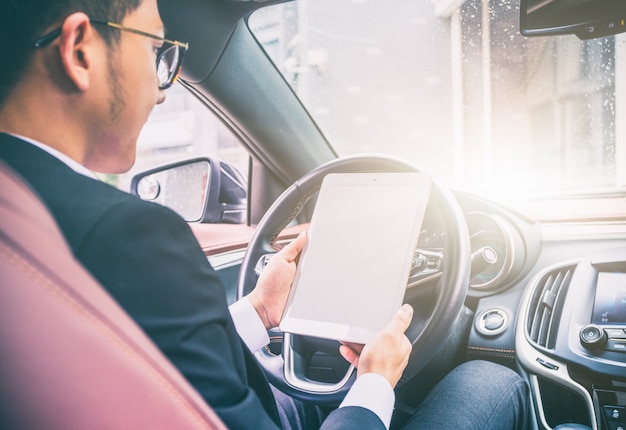 Los hombres de negocios trabajan con las computadoras tablet en sus coches