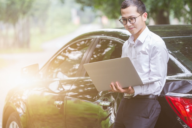 Los hombres de negocios trabajan con ordenadores portátiles en el lado del coche