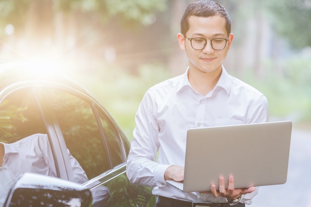 Los hombres de negocios trabajan con ordenadores portátiles en el lado del coche