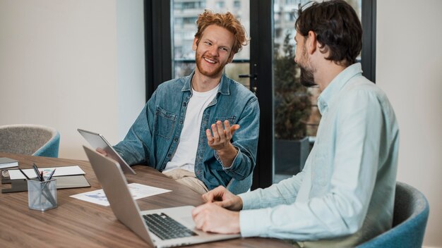 Hombres de negocios de vista lateral hablando en interiores