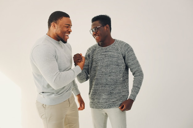 Hombres negros guapos de pie sobre una pared blanca