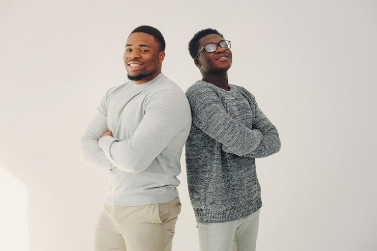 Foto gratuito hombres negros guapos de pie sobre una pared blanca