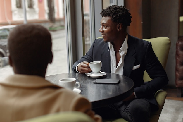 Hombres negros sentados en un café y tomando un café