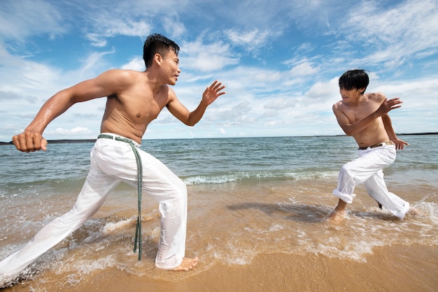 Hombres en la playa practicando capoeira juntos