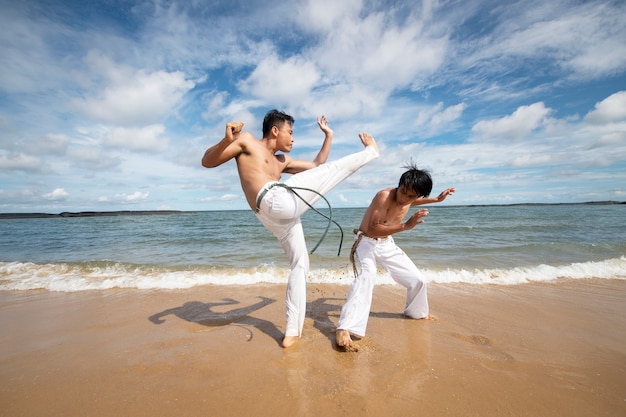 Foto gratuita hombres en la playa practicando capoeira juntos