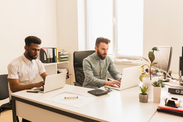 Hombres que trabajan en computadoras portátiles