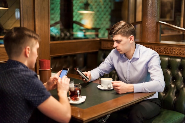 Hombres que usan teléfonos inteligentes en el restaurante
