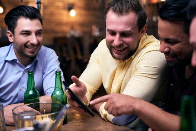 Hombres que utilizan el teléfono móvil durante la reunión en el pub