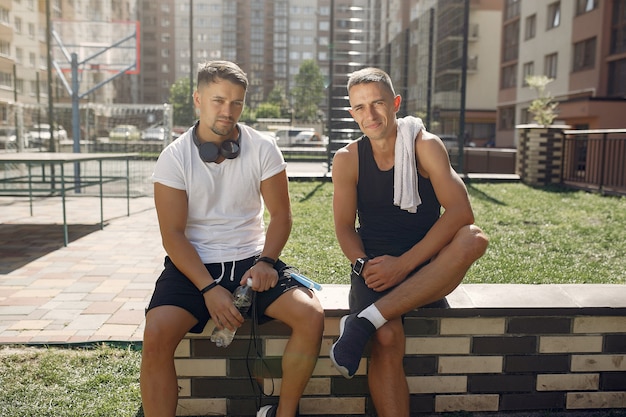 Los hombres en ropa deportiva descansan después de entrenar en un parque