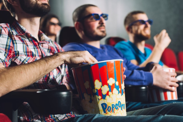 Foto gratuita hombres sin rostro mirando películas en el cine