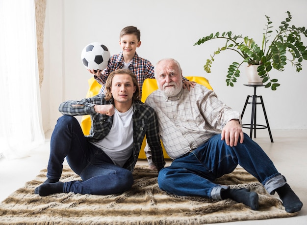 Foto gratuita hombres sentados en la alfombra y viendo fútbol.
