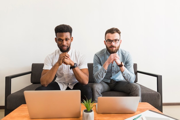 Hombres serios con computadoras portátiles