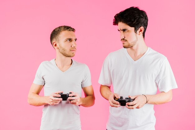 Hombres sombríos con joysticks mirándose