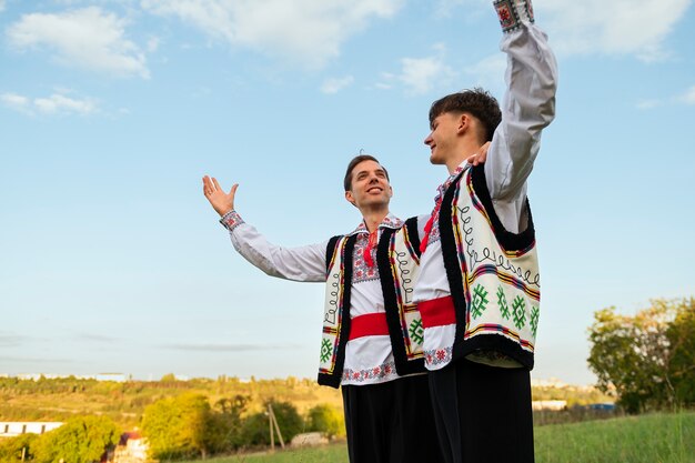 Hombres sonrientes de ángulo bajo con ropa tradicional