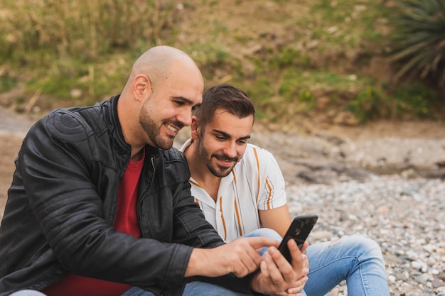 Foto gratuita hombres sonrientes revisando móvil