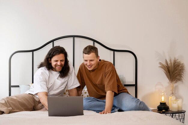 Hombres sonrientes de tiro completo mirando la computadora portátil