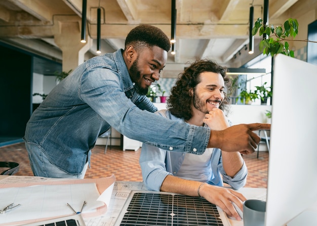 Hombres sonrientes de tiro medio mirando la computadora