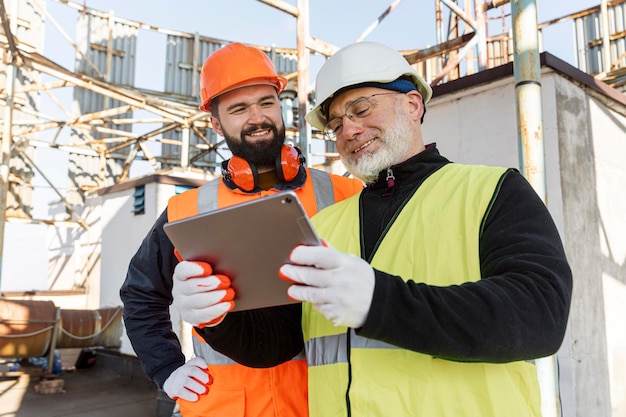 Hombres sonrientes de tiro medio con tableta