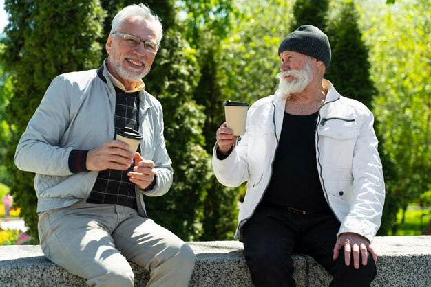 Hombres sonrientes de tiro medio con tazas de café