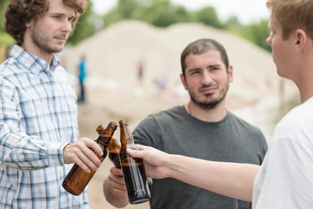 Hombres tintinean botellas en la playa