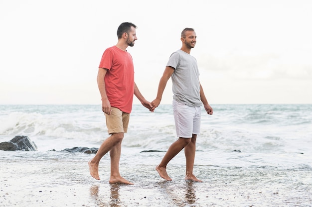 Hombres de tiro completo caminando en la playa