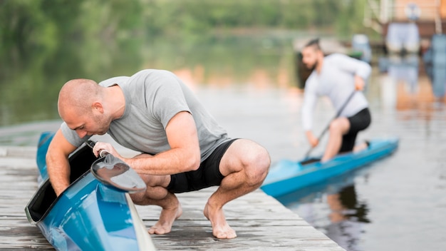 Foto gratuita hombres de tiro completo con canoas al aire libre