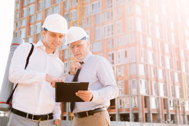 Hombres de tiro medio con andamios de construcción