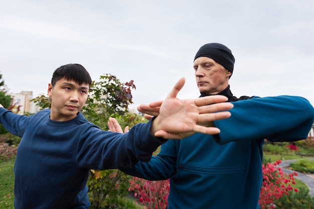 Hombres de tiro medio practicando tai chi afuera