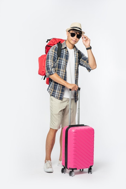 Hombres vestidos para viajar, con gafas y sombreros, llevando bolsas y equipaje.