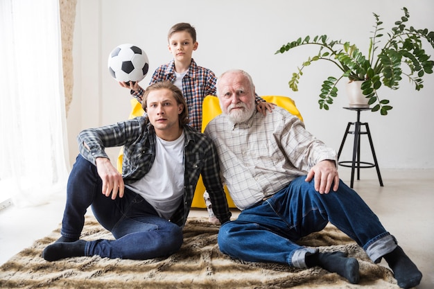 Hombres viendo fútbol sentado en la alfombra en casa