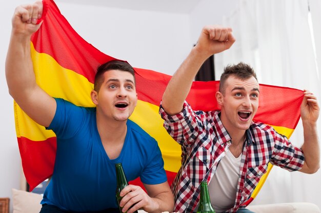 Hombres viendo un partido de fútbol en la televisión y vítores del equipo español