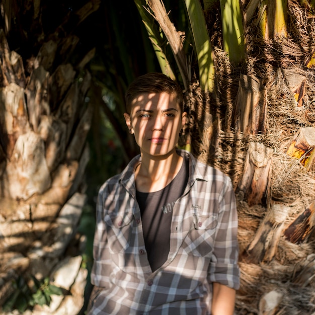 Foto gratuita homosexual parado en la sombra cerca del árbol