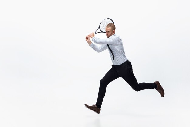 Hora de moverse. Hombre en ropa de oficina juega tenis aislado en blanco.