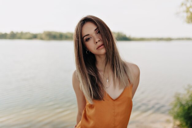 Horizontal retrato de modelo bonita con estilo en traje elegante posando sobre el lago