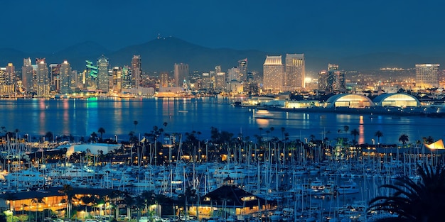 El horizonte del centro de San Diego por la noche con un barco en el puerto.