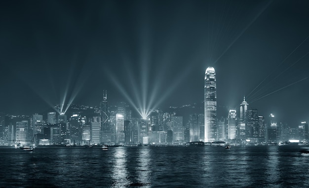 Horizonte de Hong Kong por la noche con luces y rascacielos con rayos láser en blanco y negro