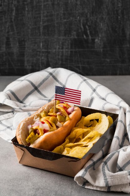 Hot-dog de alto ángulo con patatas fritas y bandera americana