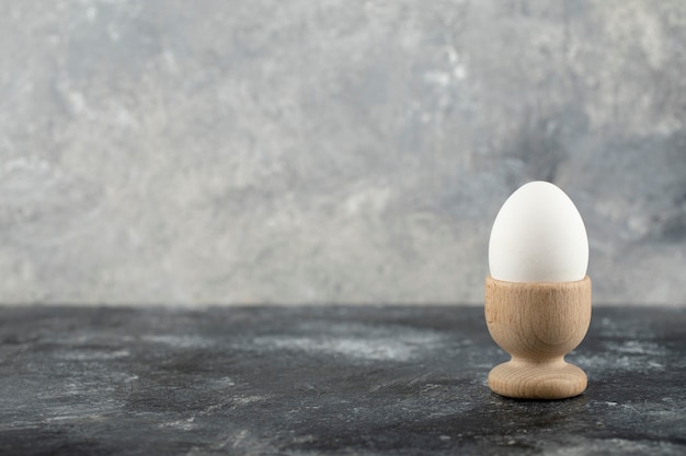 Una huevera de madera con huevo de gallina cocido.