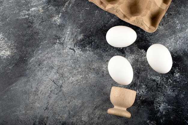 Una huevera de madera con huevos de gallina cocidos.