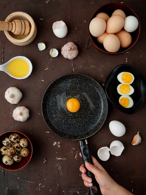 huevo, ajo con mantequilla y yema de huevo en una sartén sobre la mesa granate