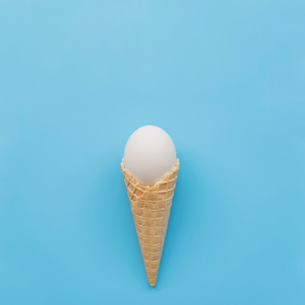 Huevo blanco en cuerno de galleta sobre fondo azul