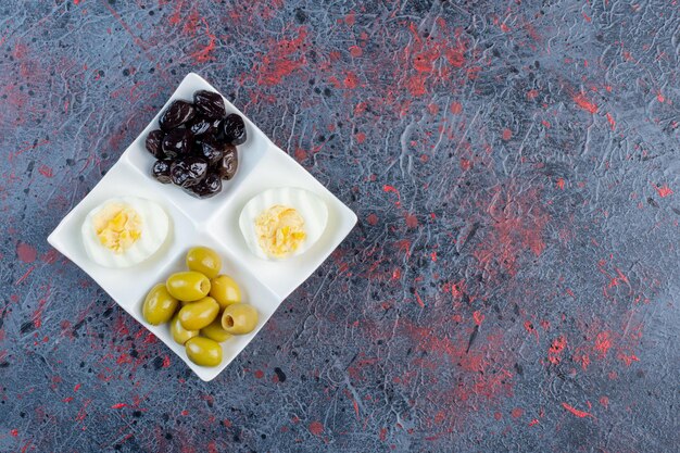 Huevo cocido con aceitunas negras y verdes marinadas.