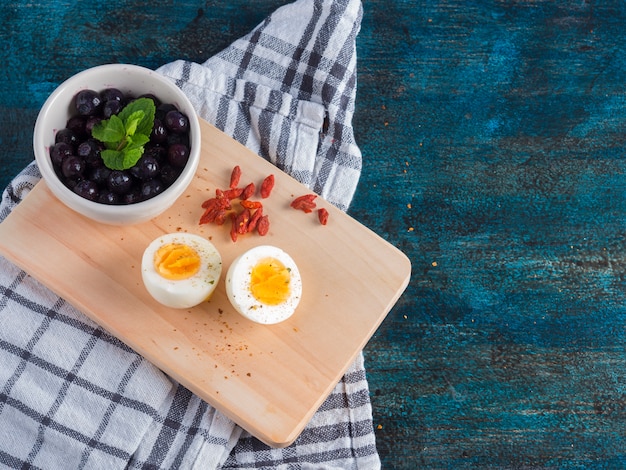 Foto gratuita huevo cocido con bayas en tablero de madera