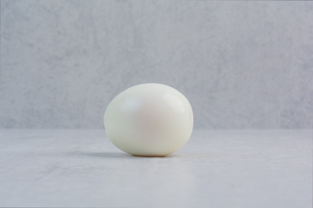 Un huevo cocido entero sobre fondo gris.