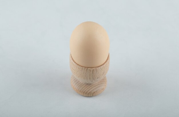 Huevo cocido en huevera sobre fondo blanco.