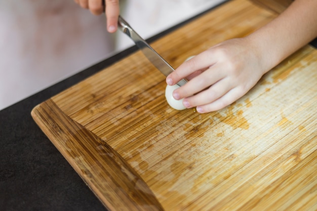 Huevo cocido de la mano de la muchacha con el cuchillo en la tabla de cortar