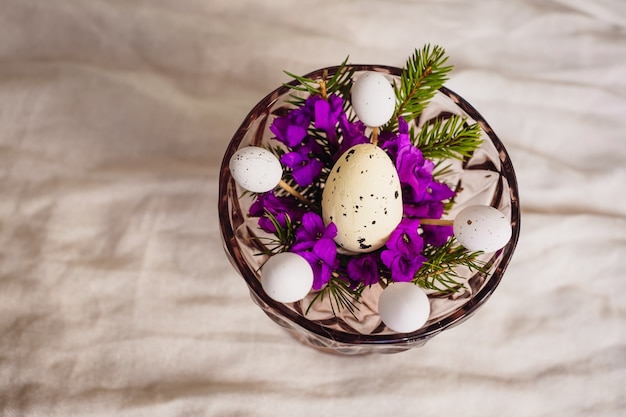 Huevo de codorniz se encuentra en las flores violetas en un tazón