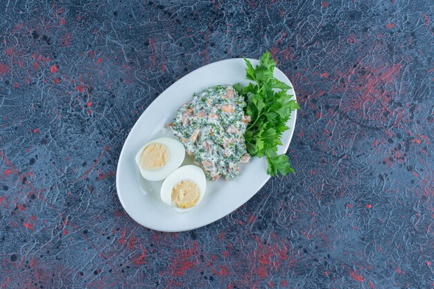 Huevo duro con ensalada en un tazón hondo blanco.